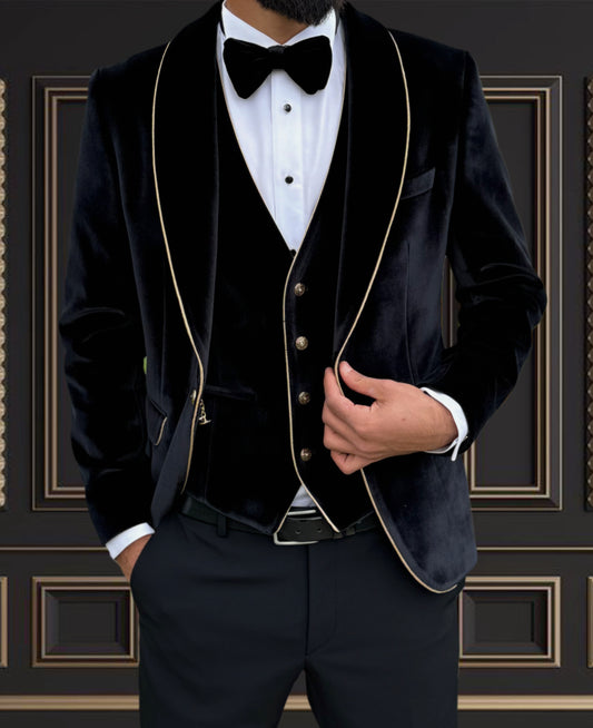 Men's black velvet tuxedo with gold trim shawl lapel, complete with vest and bowtie for formal occasions.