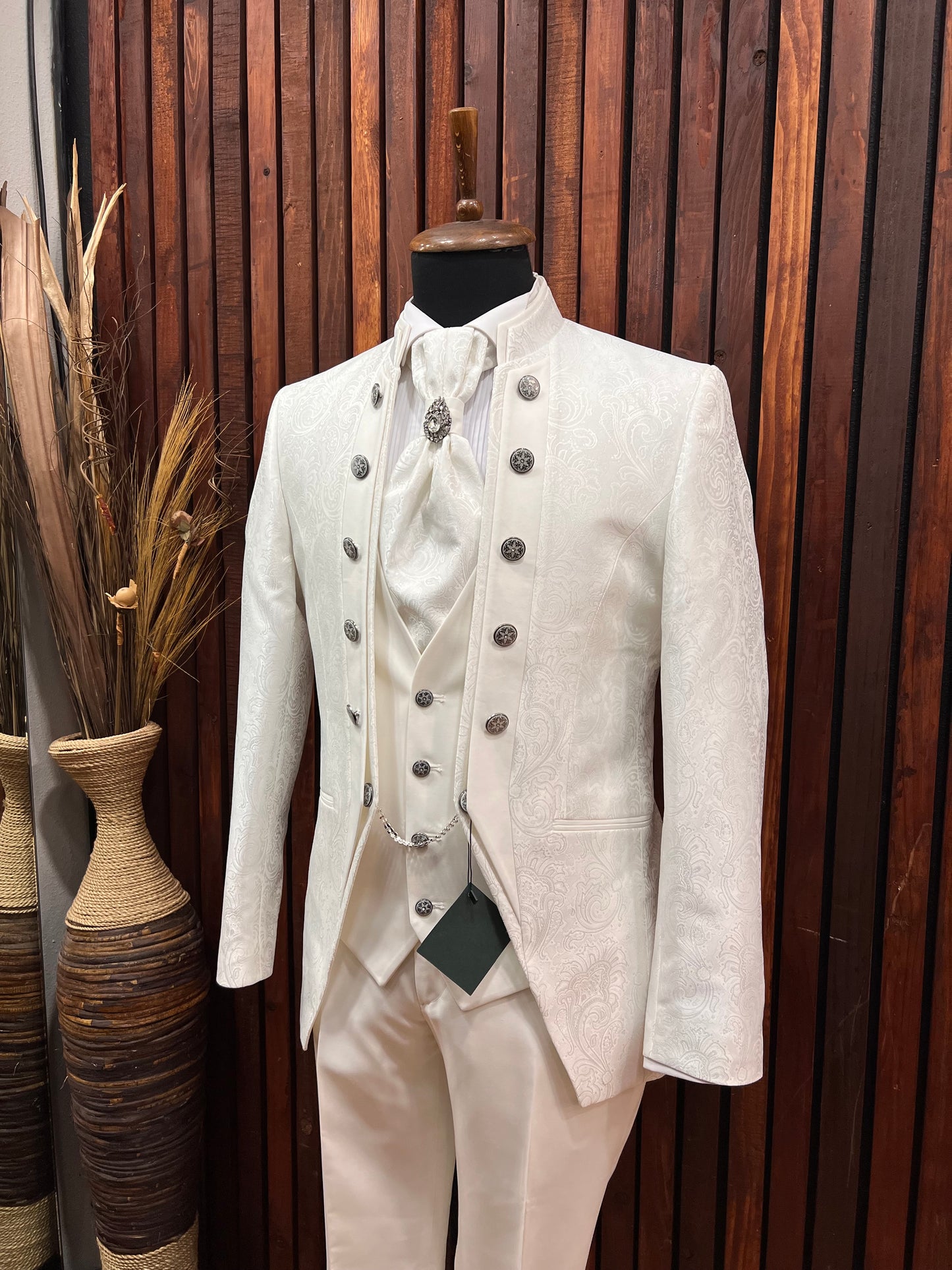 Men’s white floral tuxedo with mandarin collar displayed on mannequin, perfect for upscale events.